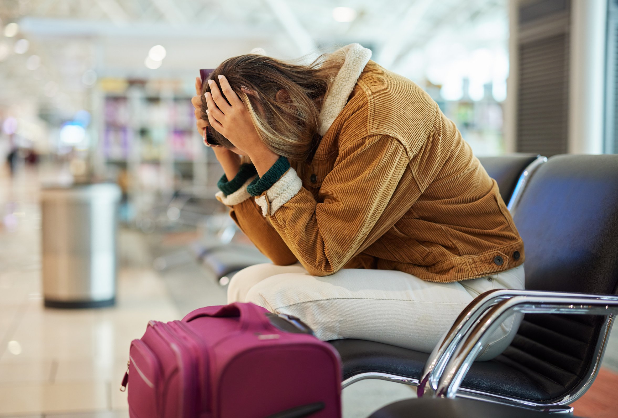 Upset Woman, Airport and Flight Delay Sitting on Bench in Travel Restrictions or Plane Cancelation with Luggage. Angry, Sad or Disappointed Female in Frustration for Missing Boarding Schedule Time